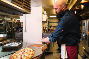 Chef making pizza in durable Indie chef coat
